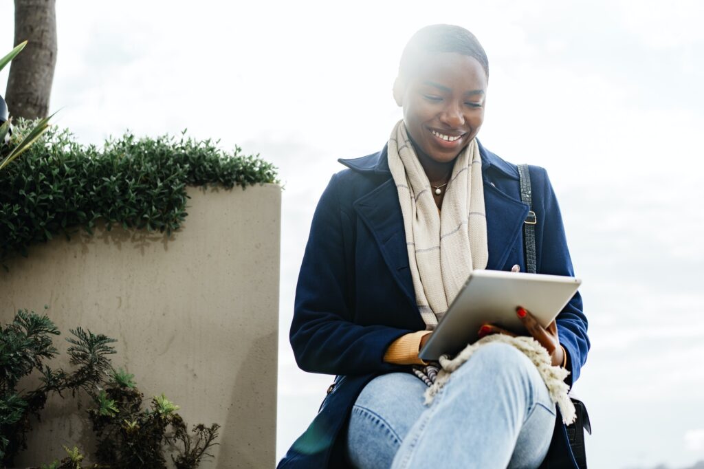 Black happy woman using a digital tablet outdoors