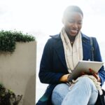 Black happy woman using a digital tablet outdoors